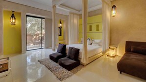 A spacious bedroom with a four-poster bed, a sitting area with a sofa, and a large window offering a view of the outdoors. - The Garden of Siredrah, an Oasis with Pool and Hammam (Marrakech)
