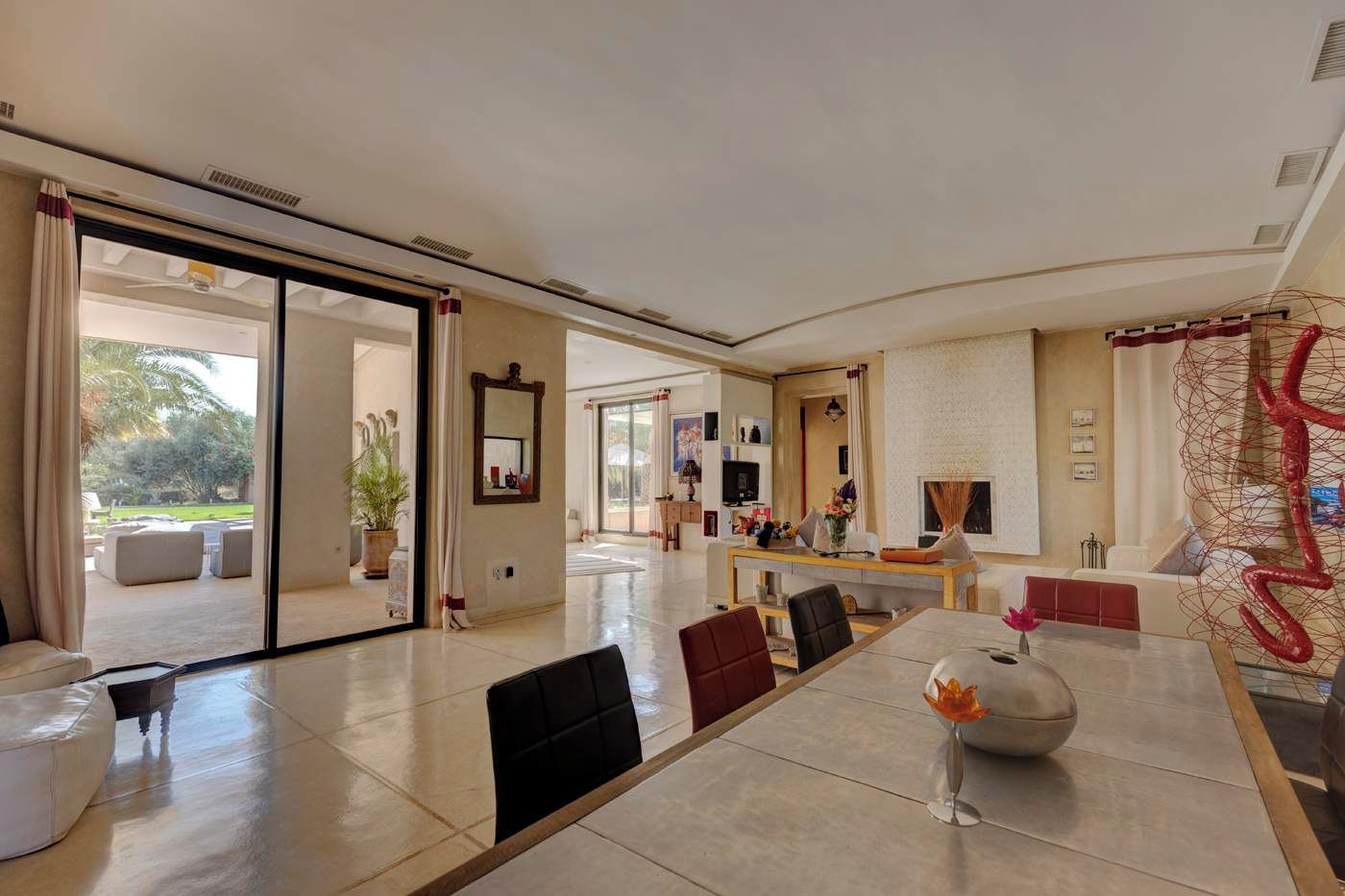 A spacious living area with a large dining table, comfortable seating, and a view of the outdoors.