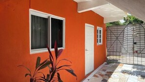 A building with an orange exterior, a white door, and a window with a curtain. - welcome to a private self contained  unit  with WIFI , A.C  , private entrance  (Kingston)