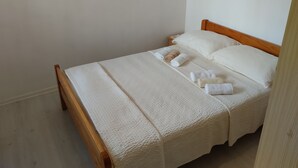 En säng med plats för en person, med en träram, vita sängkläder och två kuddar.