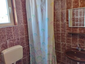 A bathroom with a toilet, sink, and shower curtain with a shell pattern. - Seaview Apartment with terrace - 1 (Žaborić)