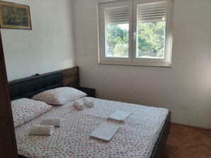 Cama bem arrumada com colcha de bolinhas, travesseiros e toalhas enroladas.
