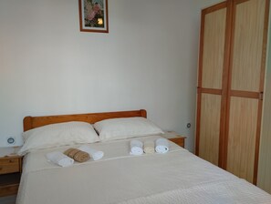 A neatly made bed with white linens and towels, a wooden headboard, and a small bedside table with a lamp. - Seaview Apartment with terrace - 1 (Žaborić)