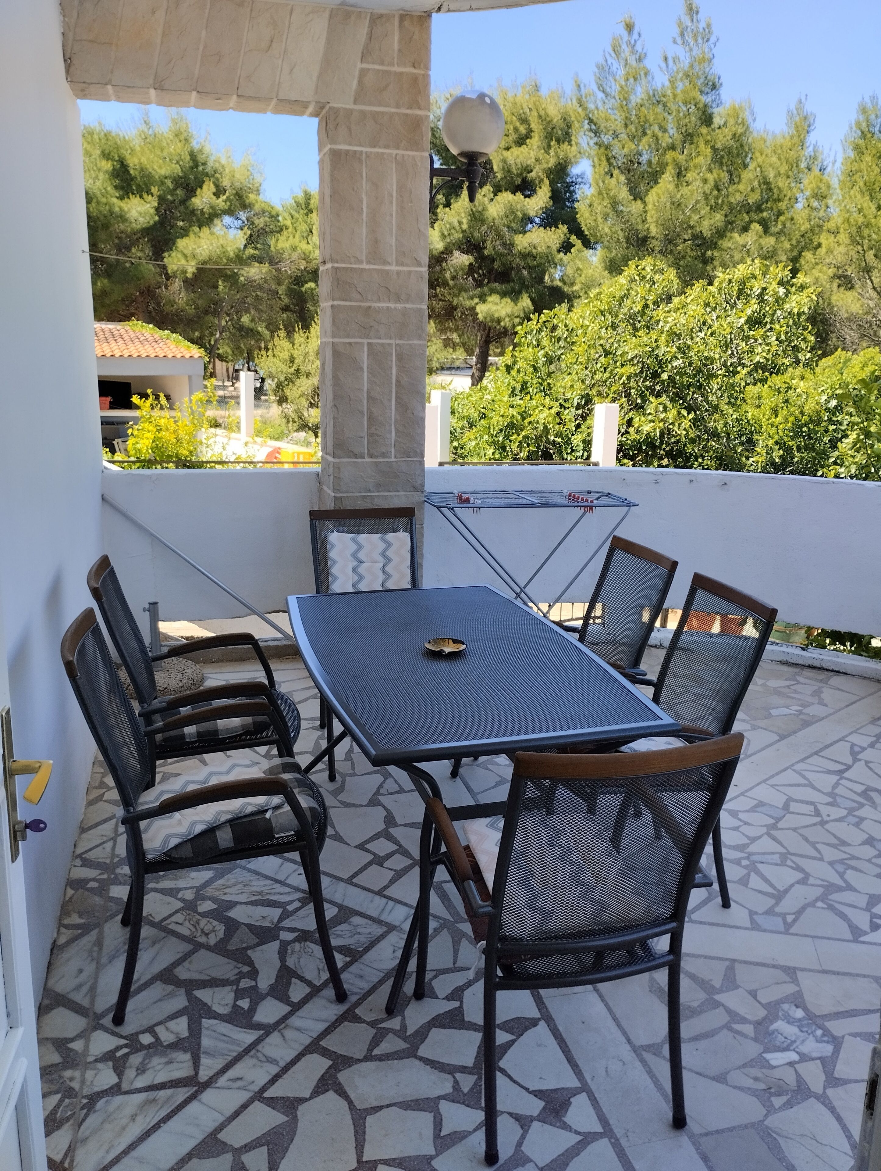 Une terrasse extérieure avec une table et des chaises, une pergola et une vue sur les arbres et les bâtiments.