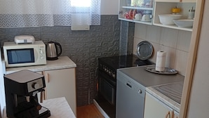 Uma cozinha compacta com micro-ondas, cafeteira, fogão e máquina de lavar louça.