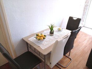 Ett matbord med en spetsduk, en skål med citroner, en liten krukväxt och ett glas vatten.