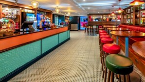 A bar area with a counter, stools, and hanging lights.