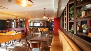 A restaurant interior with booths, tables, and hanging pendant lights.