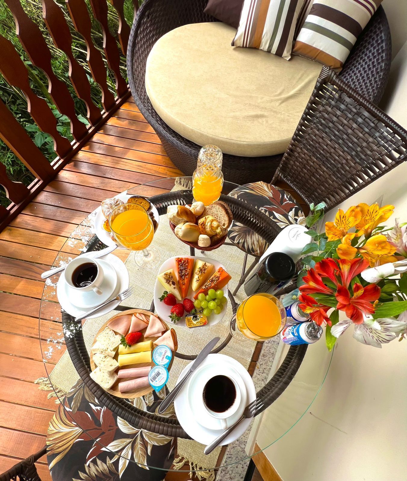 Une table ronde dressée pour le petit-déjeuner, avec divers aliments, des boissons et un arrangement floral.