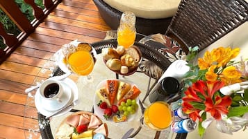Une table ronde dressée pour le petit-déjeuner, avec divers aliments, des boissons et un arrangement floral.