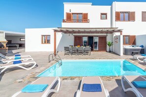 A poolside area with lounge chairs, a dining table, and a covered patio.