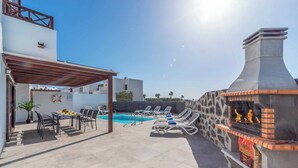 Une terrasse sur le toit avec une piscine, des chaises longues, un barbecue et une pergola.