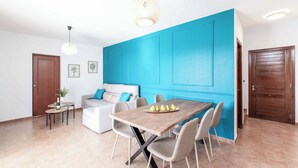 Un salon moderne avec une table à manger en bois, un canapé et un mur d’accent bleu.