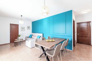Una sala moderna con una mesa de comedor de madera, un sofá y una pared azul decorativa.
