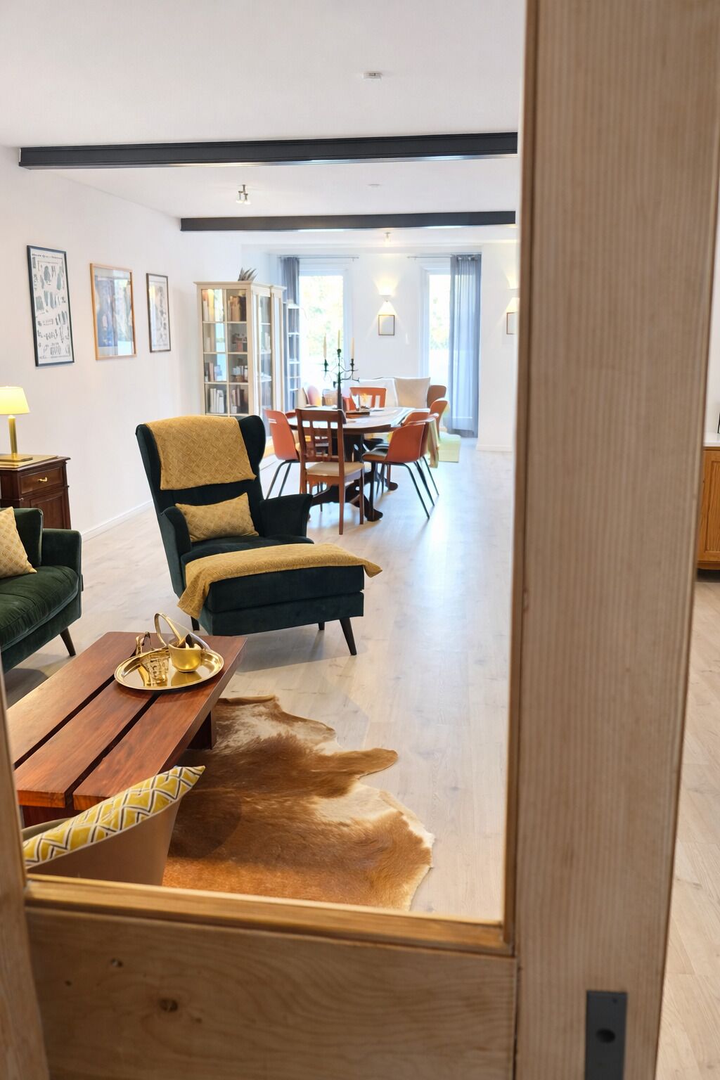 A modern living room with a sofa, a coffee table, and a dining area in the background.