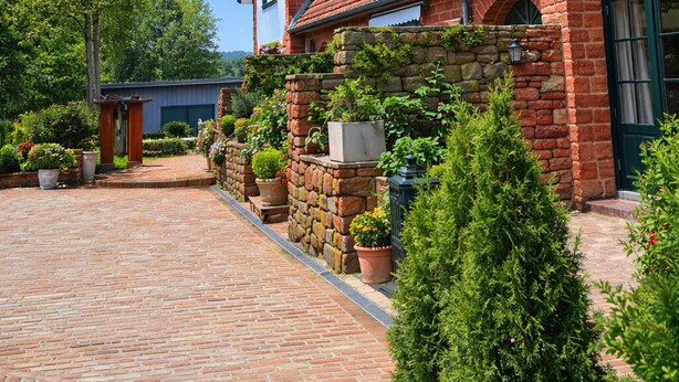 A brick house with a red-tiled roof and a stone wall. - Apartment "Romantik" - an apartment with a special character (Mürlenbach)