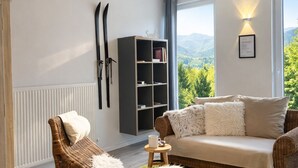 A modern living room with a wicker lounge chair, a sofa, a bookshelf, and a view of the outdoors. - Apartment "Romantik" - an apartment with a special character (Mürlenbach)