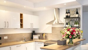 A modern kitchen with white cabinets, a wooden countertop, a central island, a wine rack, and a vase of flowers. - Apartment "Romantik" - an apartment with a special character (Mürlenbach)