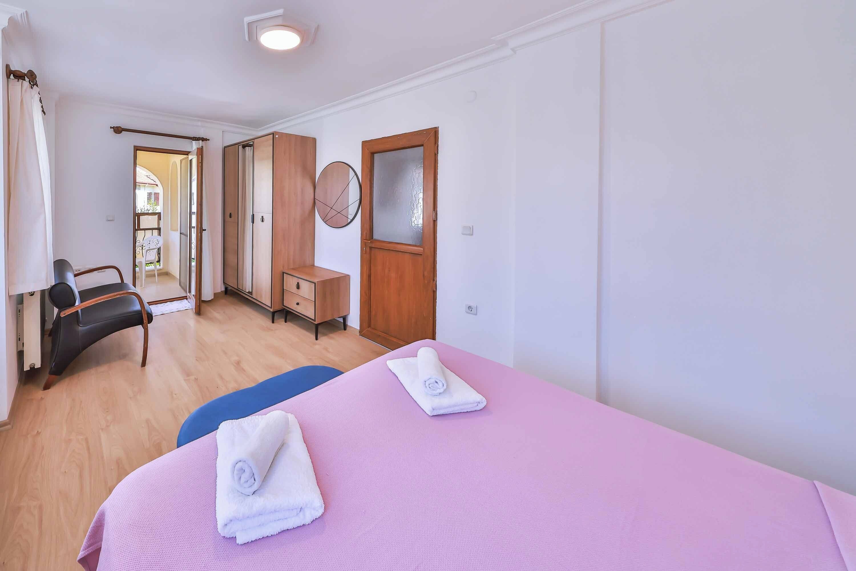 Una habitación de hotel con una cama, una silla, un escritorio y un armario.