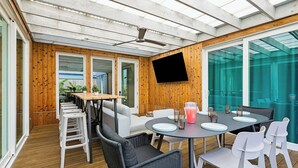 A modern dining area with a round table, white chairs, and a ceiling fan.