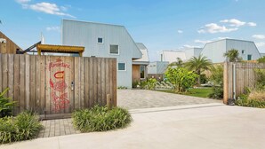 A modern building with a wooden gate, a paved driveway, and a well-maintained lawn.