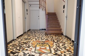 Un couloir doté d’un sol en mosaïque menant à un escalier.