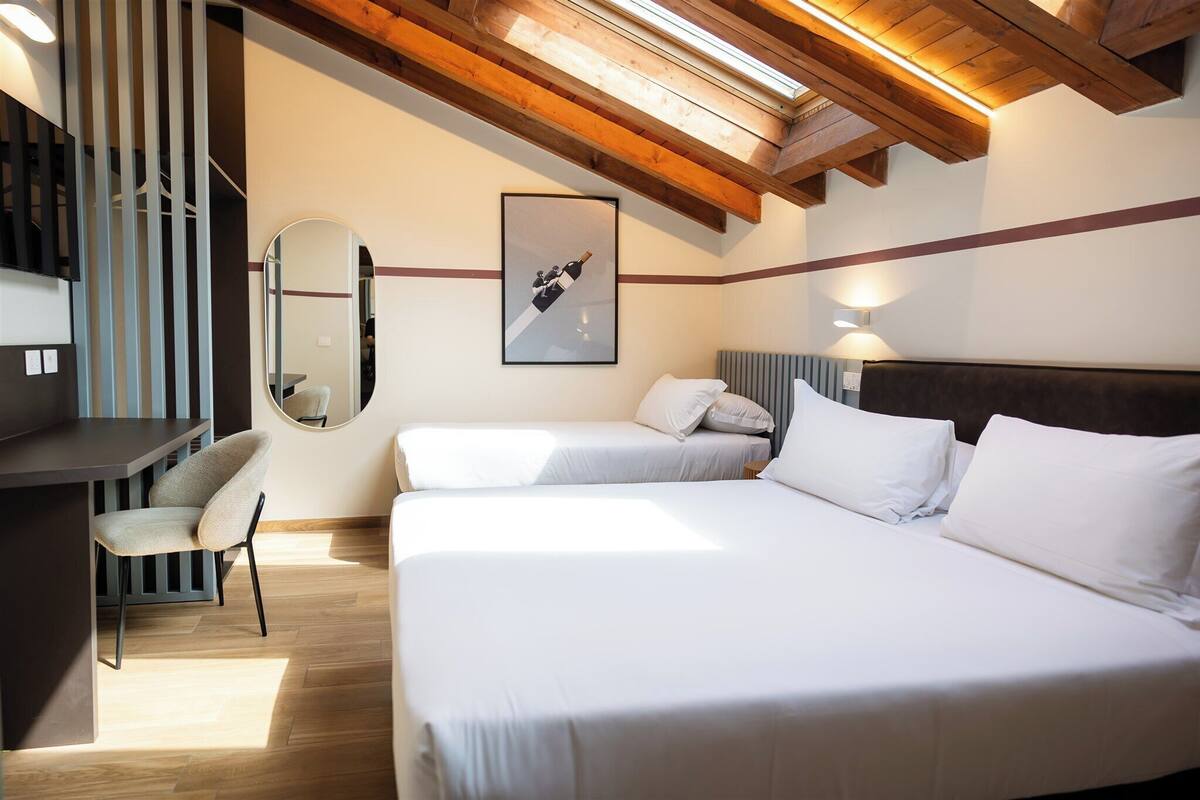 Un dormitorio con dos camas, un escritorio, una silla, un espejo y un cuadro en la pared.