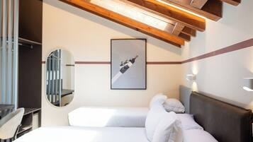 A bedroom with a bed, a bedside table, a mirror, and a framed picture on the wall.