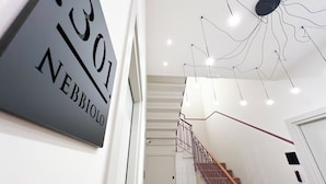 A modern interior with a staircase, a unique ceiling light fixture, and a sign with the number '301'. - RossoVino Milano Boutique (Milan)