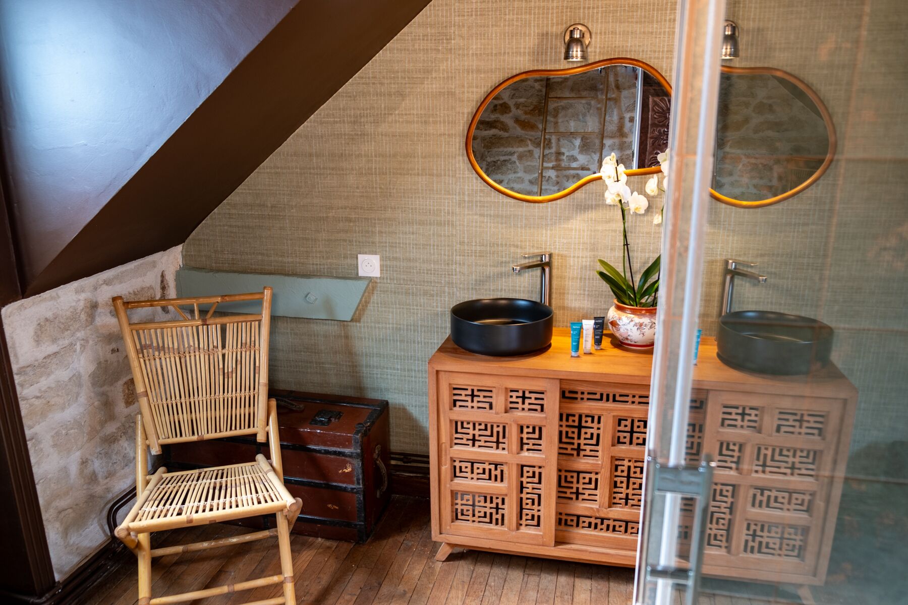 Een badkamer met een houten stoel, een spiegel, een wastafel en een decor kast.