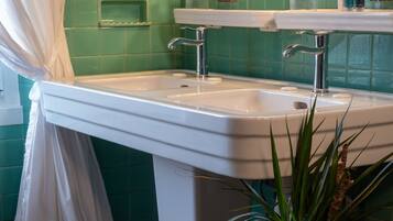 A bathroom with a white sink, green tiles, and a mirror above it.