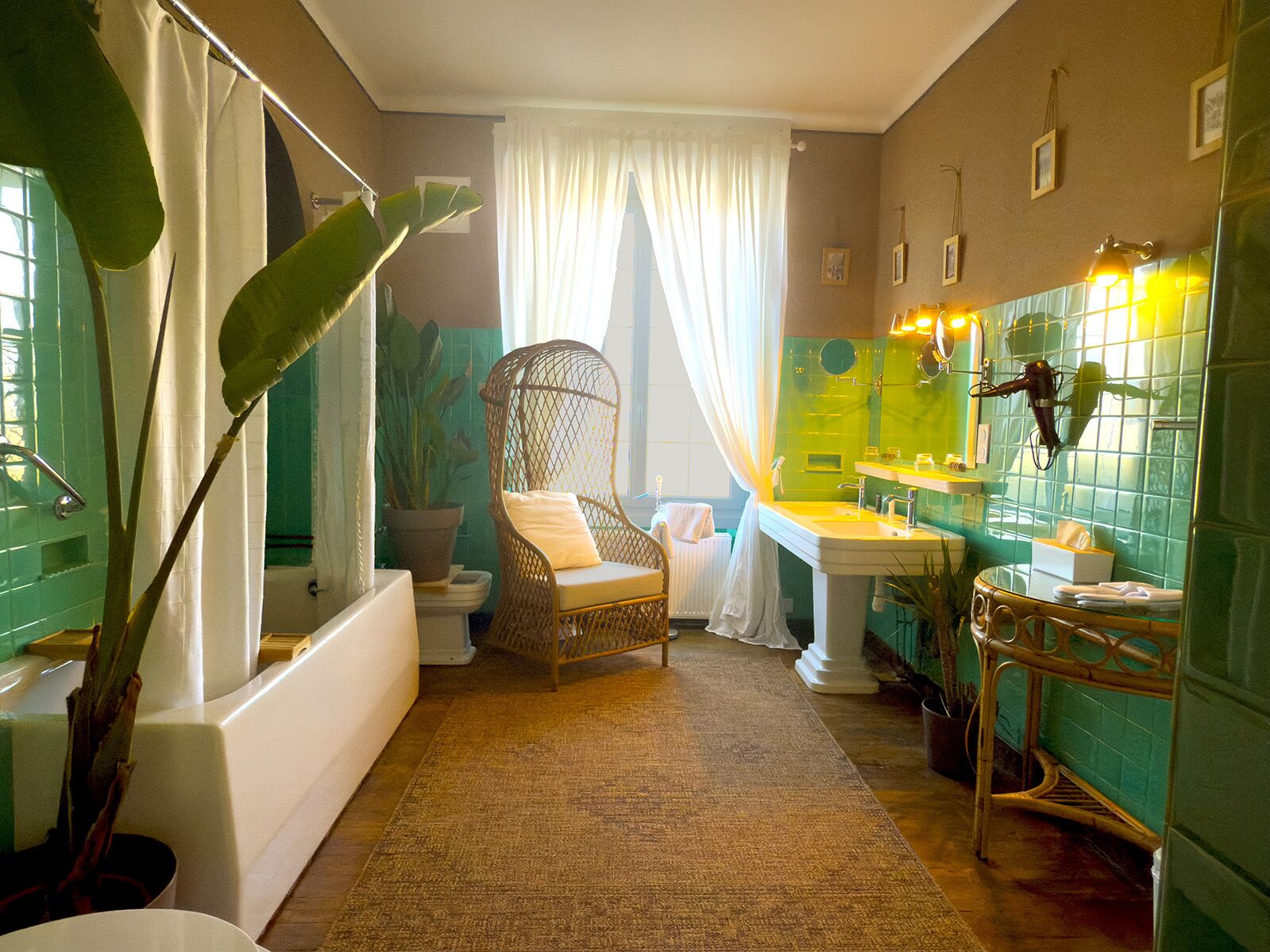Une salle de bain avec une baignoire, un fauteuil en osier, un lavabo et un miroir.