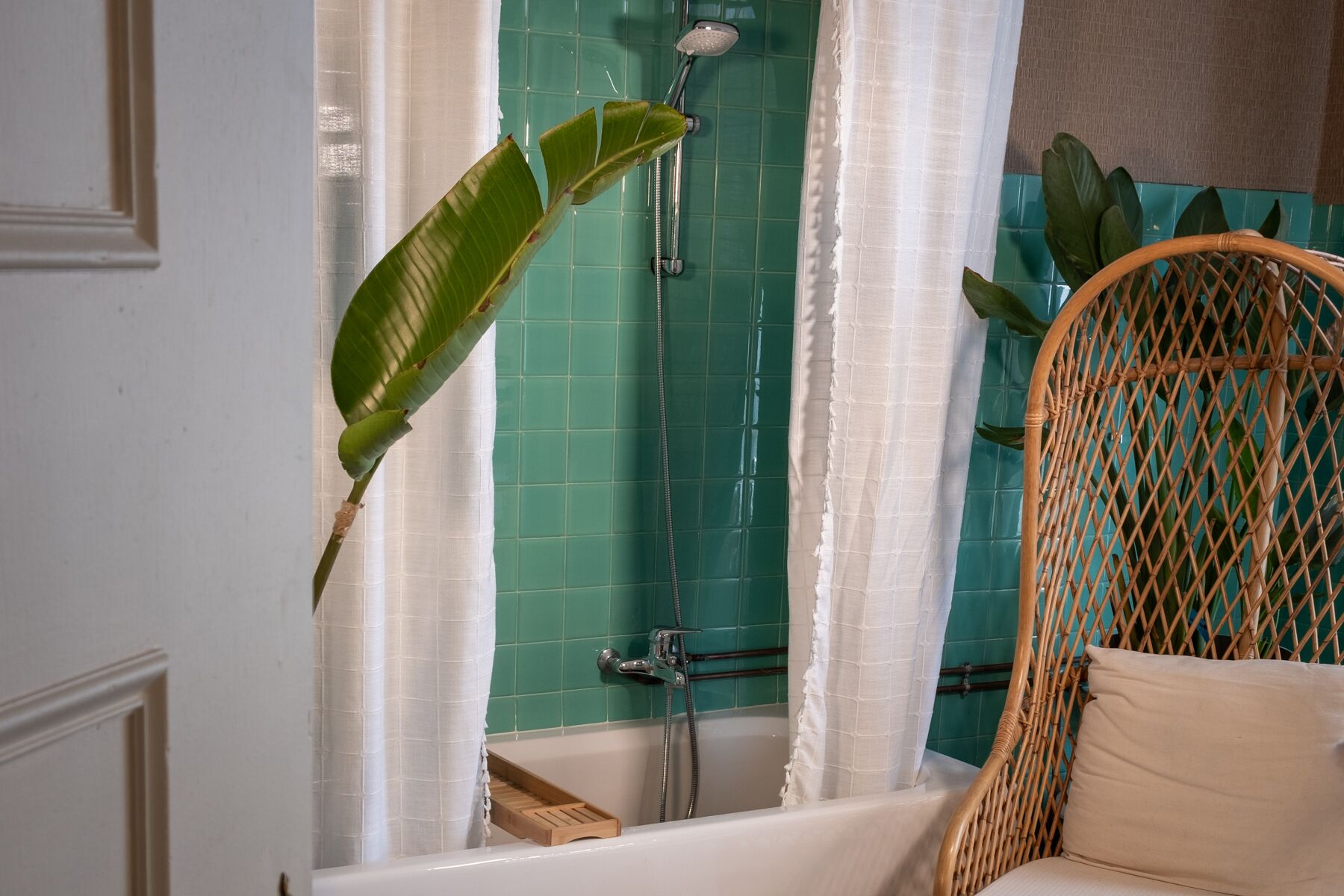 Un baño con ducha, bañera y una silla de mimbre.