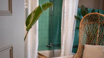 Un baño con ducha, bañera y una silla de mimbre.