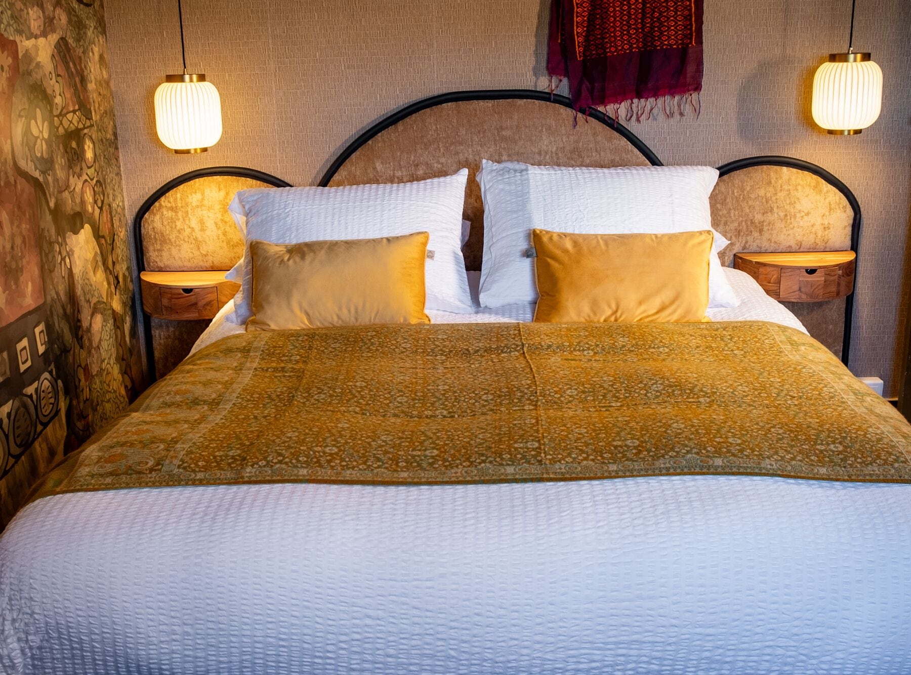 Ein Bett mit einem gemusterten Überwurf, zwei Kissen und zwei Nachttischlampen.