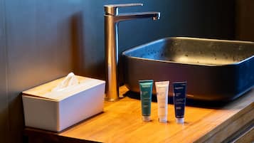 A bathroom sink with a tissue box and three bottles of Algotherm body cream.