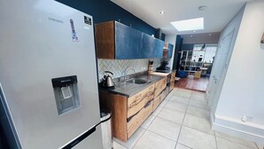 A modern kitchen with a stainless steel refrigerator, wooden cabinets, and a tiled floor. - Westmeads wings. 5 minutes walk to the harbour and close to town and beach (Whitstable)