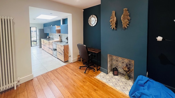 A modern kitchen with a view to the dining area, a clock on the wall, and a decorative wall piece. - Westmeads wings. 5 minutes walk to the harbour and close to town and beach (Whitstable)