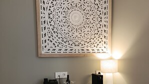 Un escritorio con una computadora, una lámpara y un panel decorativo.