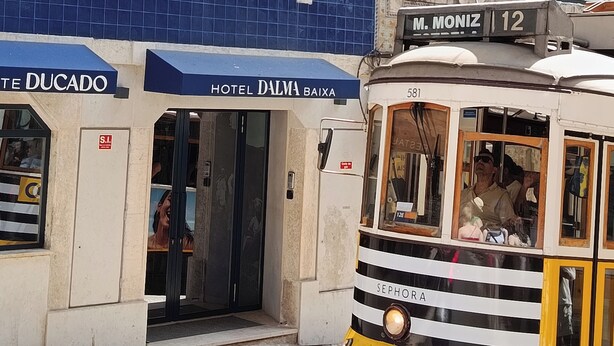 A yellow tram with the number 581, passing in front of a building with a blue tiled facade and a sign for 'Hotel Dalma Baixa'. - Dalma Baixa (Lisbon)
