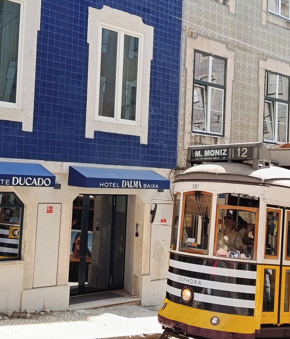 A yellow tram with the number 581, passing in front of a building with a blue tiled facade and a sign for 'Hotel Dalma Baixa'. - Dalma Baixa (Lisbon)