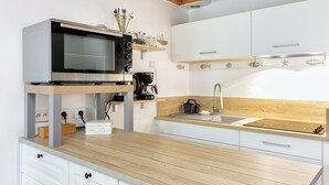 Une cuisine moderne équipée d’un four à micro-ondes, d’une machine à café et d’un plan de travail en bois.