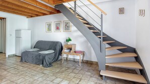 Un intérieur moderne avec un escalier, un canapé, une petite table agrémentée d’une plante et des tableaux encadrés accrochés au mur.