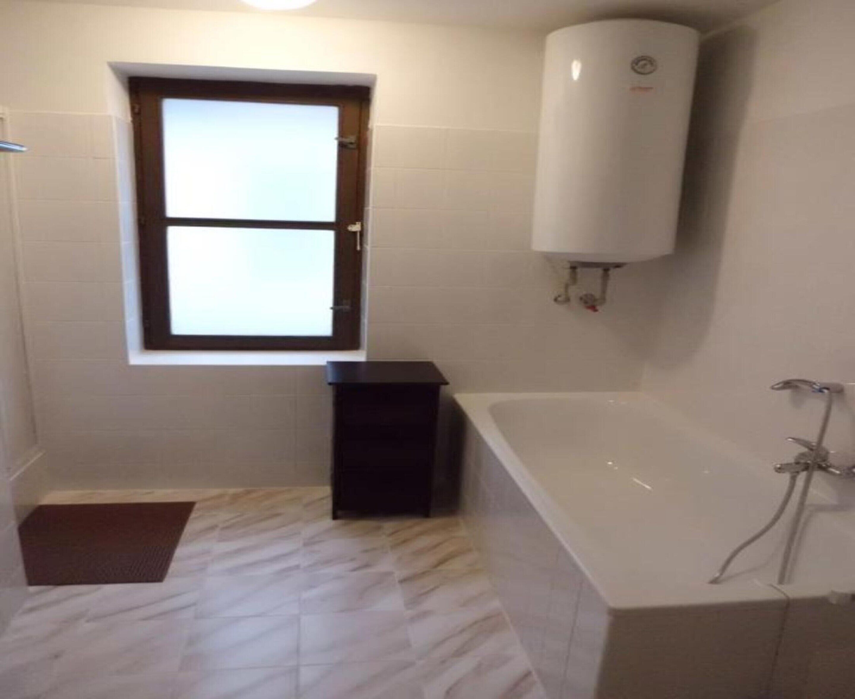 A bathroom with a window, a white toilet, a bathtub, and a shower.
