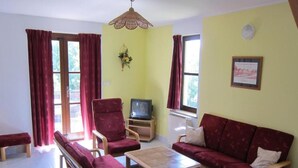 A living room with a sofa, two armchairs, a coffee table, a television on a stand, and a window with curtains. - Serene Mansion With Pool (Starkov)