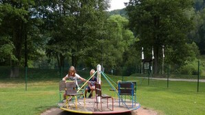 A playground with a merry-go-round and swings in a park. - Serene Mansion With Pool (Starkov)