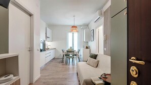 Een smalle gang met een eethoek, kitchenette en een bank met salontafel.