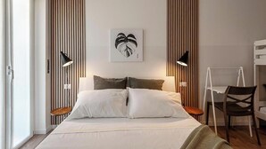Een moderne slaapkamer met een bed, twee nachtkastjes, een stoel en een aan de muur bevestigd kunstwerk.
