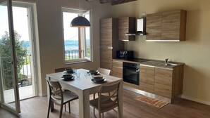A modern kitchen with wooden cabinets, a built-in oven, and a window overlooking a balcony.