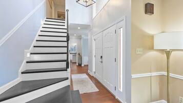 A staircase with black and white steps leading to a landing, a white floor lamp, and a beige wall with a door.